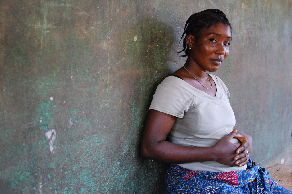 Pregnant woman sitting against a wall